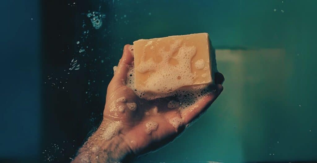 pain savon naturel dans une main d'homme poilue sous la douche bulle mousse sans produit chimique