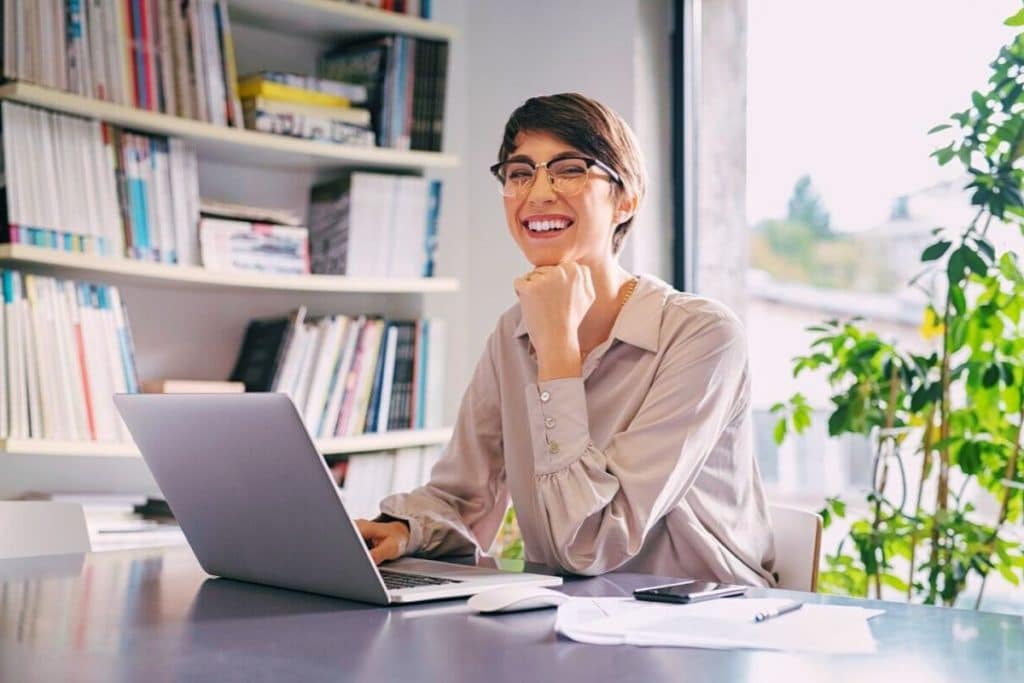 femme à lunette sur son macbook pro gris argent télétravail souris apple prise de note