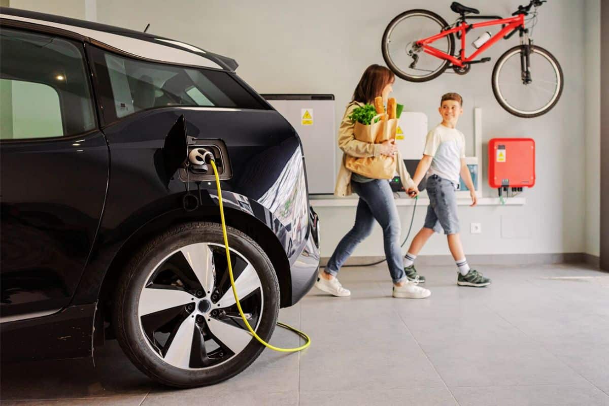 Voiture électrique en recharge dans le garage d'une maison individuelle