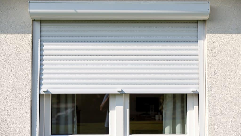 Volet roulant PVC blanc bloqué à mi-hauteur sur une fenêtre de maison