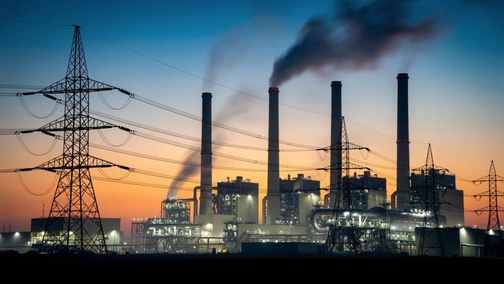 Centrale thermique et pylônes au crépuscule, illustrant pourquoi l'électricité est si chère en France