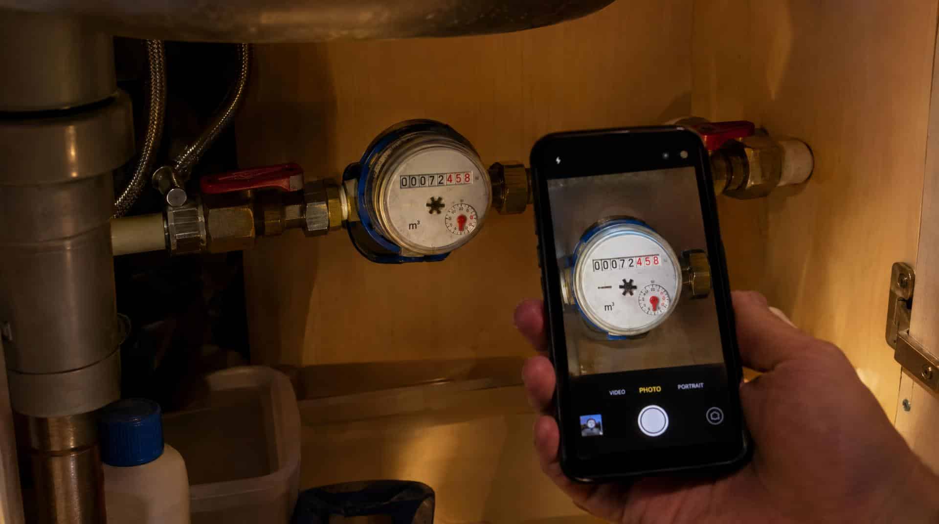 Relevé de l'index d'un compteur d'eau sous l'évier, photographié au smartphone le soir pour le test de fuite