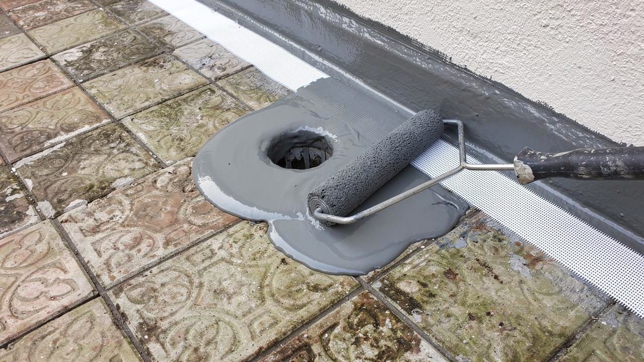 Système d’étanchéité liquide appliqué au rouleau sur un carrelage de terrasse existant, bande d’armature autour de l’évacuation et en pied de mur